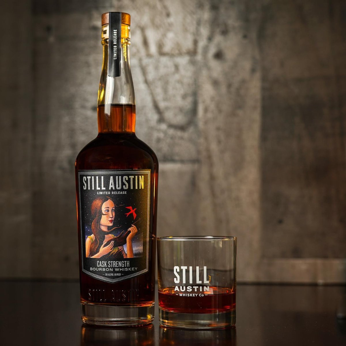 Still Austin Cask Strength Bourbon on a table with a glass with whiskey