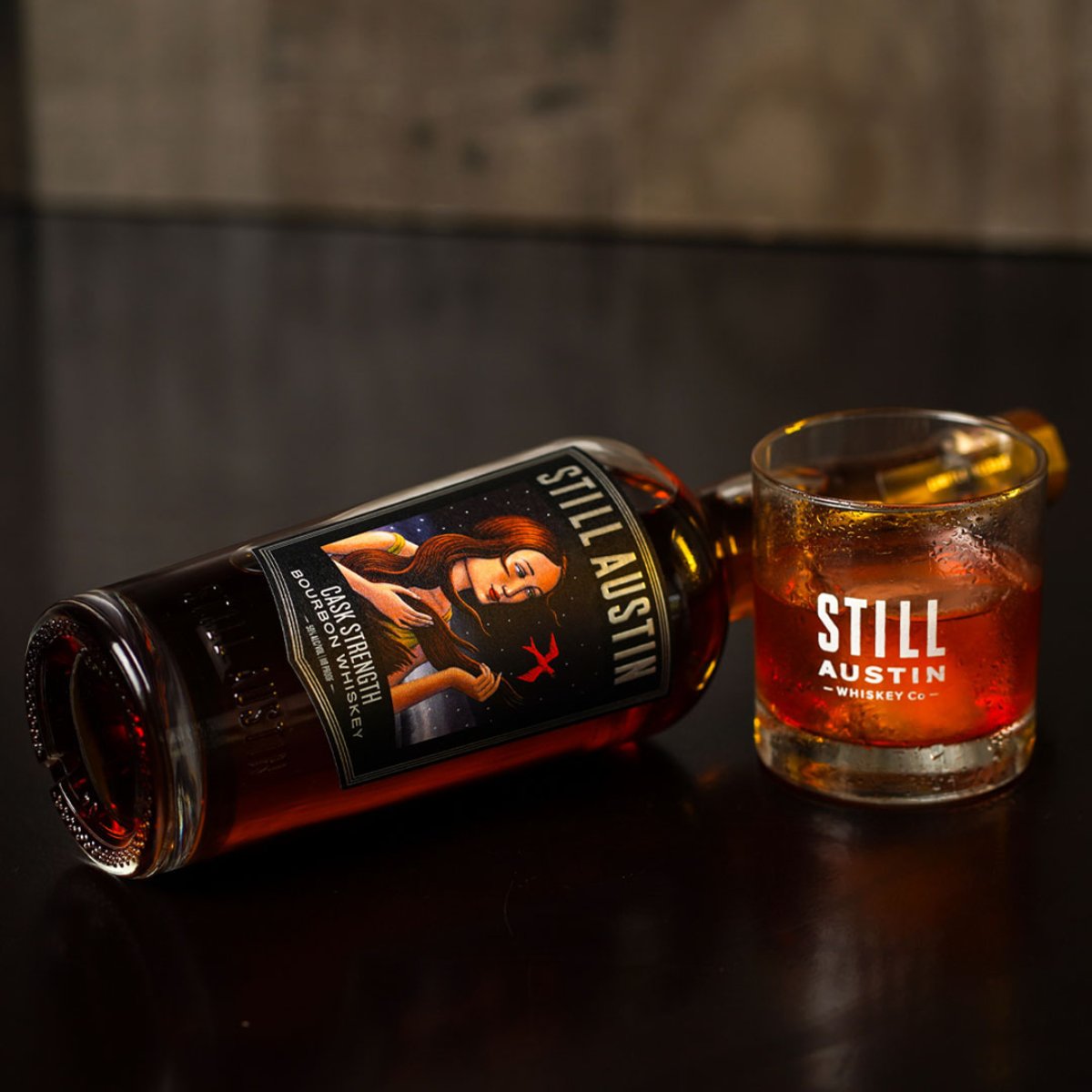 Still Austin Cask Strength Bourbon on a table with a glass with whiskey